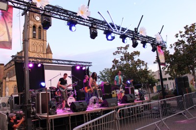 Personnes dansant et discutant lors d'une soirée en extérieur, éclairée par des lumières colorées et décorée de guirlandes.