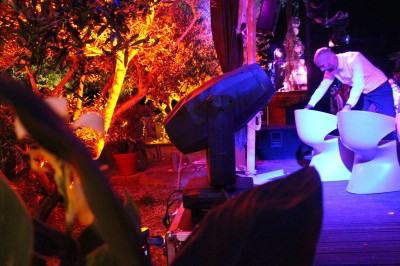 Personnes dansant et discutant lors d'une soirée en extérieur, éclairée par des lumières colorées et décorée de guirlandes.