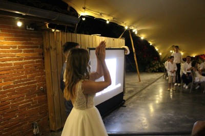 Personnes dansant et discutant lors d'une soirée en extérieur, éclairée par des lumières colorées et décorée de guirlandes.