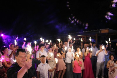 Personnes dansant et discutant lors d'une soirée en extérieur, éclairée par des lumières colorées et décorée de guirlandes.