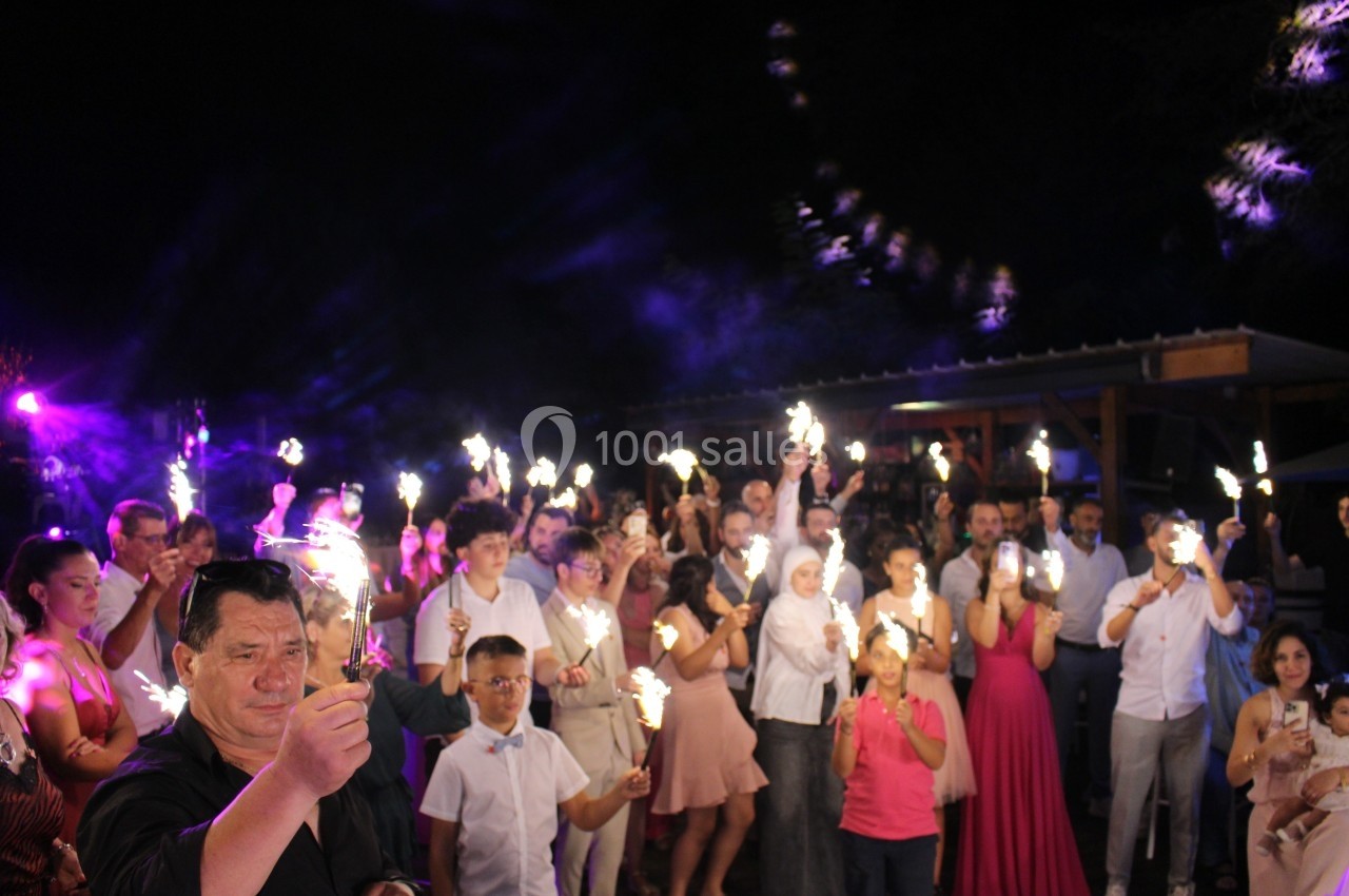 Groupe de personnes tenant des cierges magiques allumés lors d'une célébration en soirée.