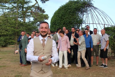 Personnes dansant et discutant lors d'une soirée en extérieur, éclairée par des lumières colorées et décorée de guirlandes.