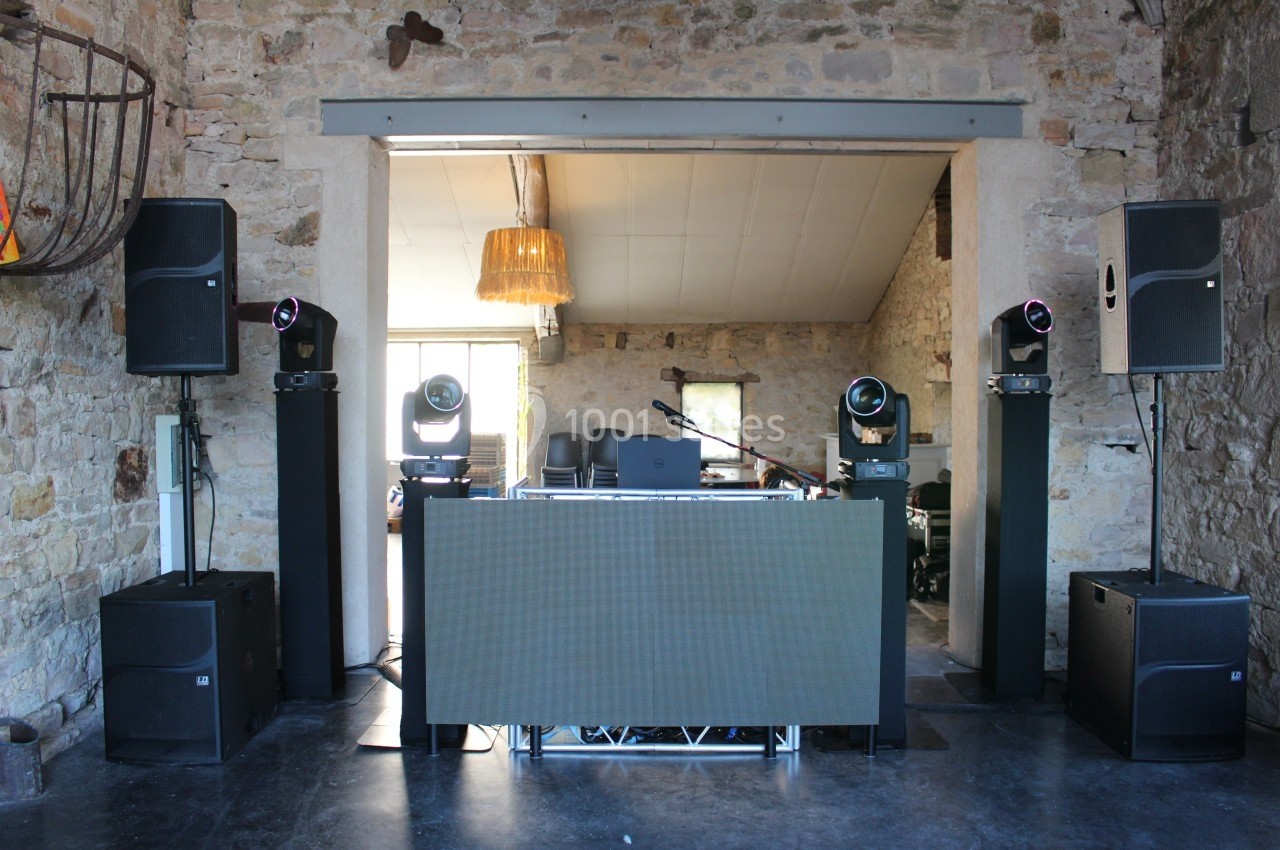 Installation de matériel de sonorisation et d'éclairage dans une salle en pierre avec une table de mixage centrale.