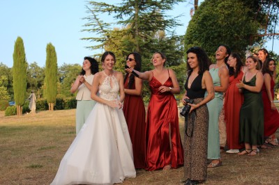 Personnes dansant et discutant lors d'une soirée en extérieur, éclairée par des lumières colorées et décorée de guirlandes.