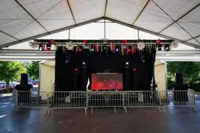 Personnes dansant et discutant lors d'une soirée en extérieur, éclairée par des lumières colorées et décorée de guirlandes.