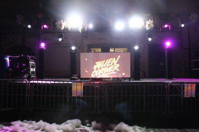 Personnes dansant et discutant lors d'une soirée en extérieur, éclairée par des lumières colorées et décorée de guirlandes.