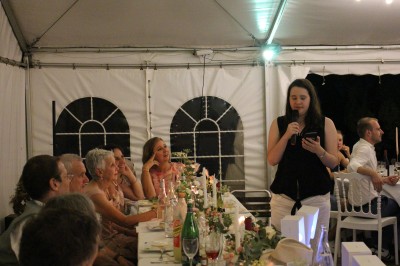 Personnes dansant et discutant lors d'une soirée en extérieur, éclairée par des lumières colorées et décorée de guirlandes.