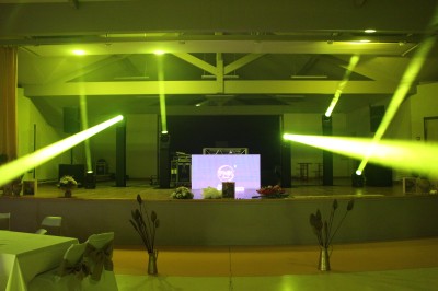 Personnes dansant et discutant lors d'une soirée en extérieur, éclairée par des lumières colorées et décorée de guirlandes.