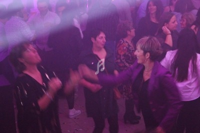 Des personnes dansent et discutent dans une ambiance festive avec éclairage tamisé et fumée légère.