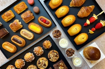 Plateaux de viennoiseries, pâtisseries et desserts variés disposés sur une table en surface claire.