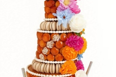 Pièce montée de choux décorée de fleurs colorées, macarons et un disque personnalisé au sommet.