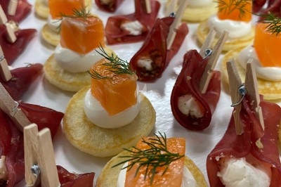 Assortiment de canapés garnis de saumon, crème et aneth, ou de viande séchée avec fromage, présentés sur un plateau.