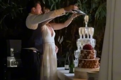 Un couple verse du champagne dans une pyramide de verres lors d'une réception en extérieur, près d'une table décorée.