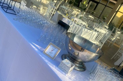 Miniature Traiteur Fréjus (Var) - La Cuisine By Alexandre #23 Salle de réception lumineuse avec tables rondes décorées de fleurs et vaisselle élégante, éclairée par des guirlandes.