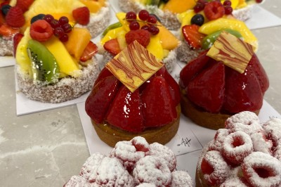 Miniature Traiteur Fréjus (Var) - La Cuisine By Alexandre #4 Salle de réception lumineuse avec tables rondes décorées de fleurs et vaisselle élégante, éclairée par des guirlandes.