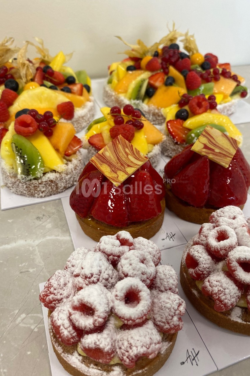 Assortiment de tartes individuelles garnies de fruits frais, dont framboises, fraises et morceaux de mangue.