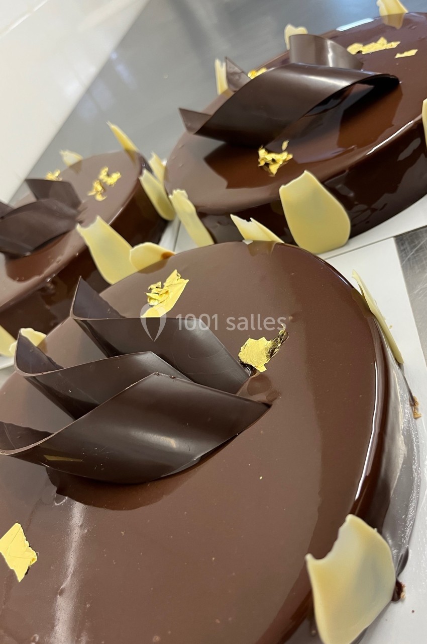 Gâteaux au glaçage chocolat brillant, décorés de feuilles en chocolat noir et blanc et touches de feuille d'or.