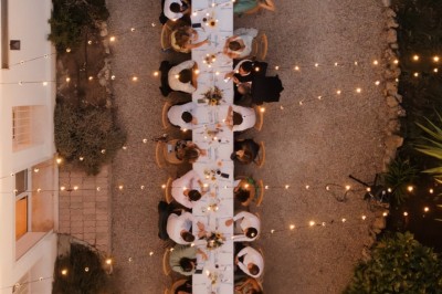 Miniature Traiteur Fréjus (Var) - La Cuisine By Alexandre #38 Salle de réception lumineuse avec tables rondes décorées de fleurs et vaisselle élégante, éclairée par des guirlandes.