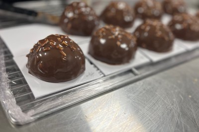 Miniature Traiteur Fréjus (Var) - La Cuisine By Alexandre #31 Salle de réception lumineuse avec tables rondes décorées de fleurs et vaisselle élégante, éclairée par des guirlandes.