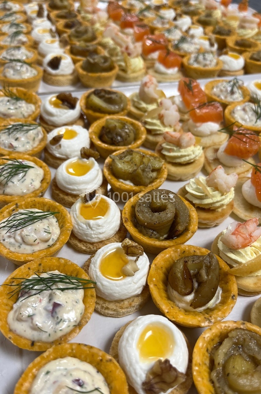Plateau de bouchées apéritives variées comprenant tartelettes, crevettes, saumon fumé et garnitures raffinées.