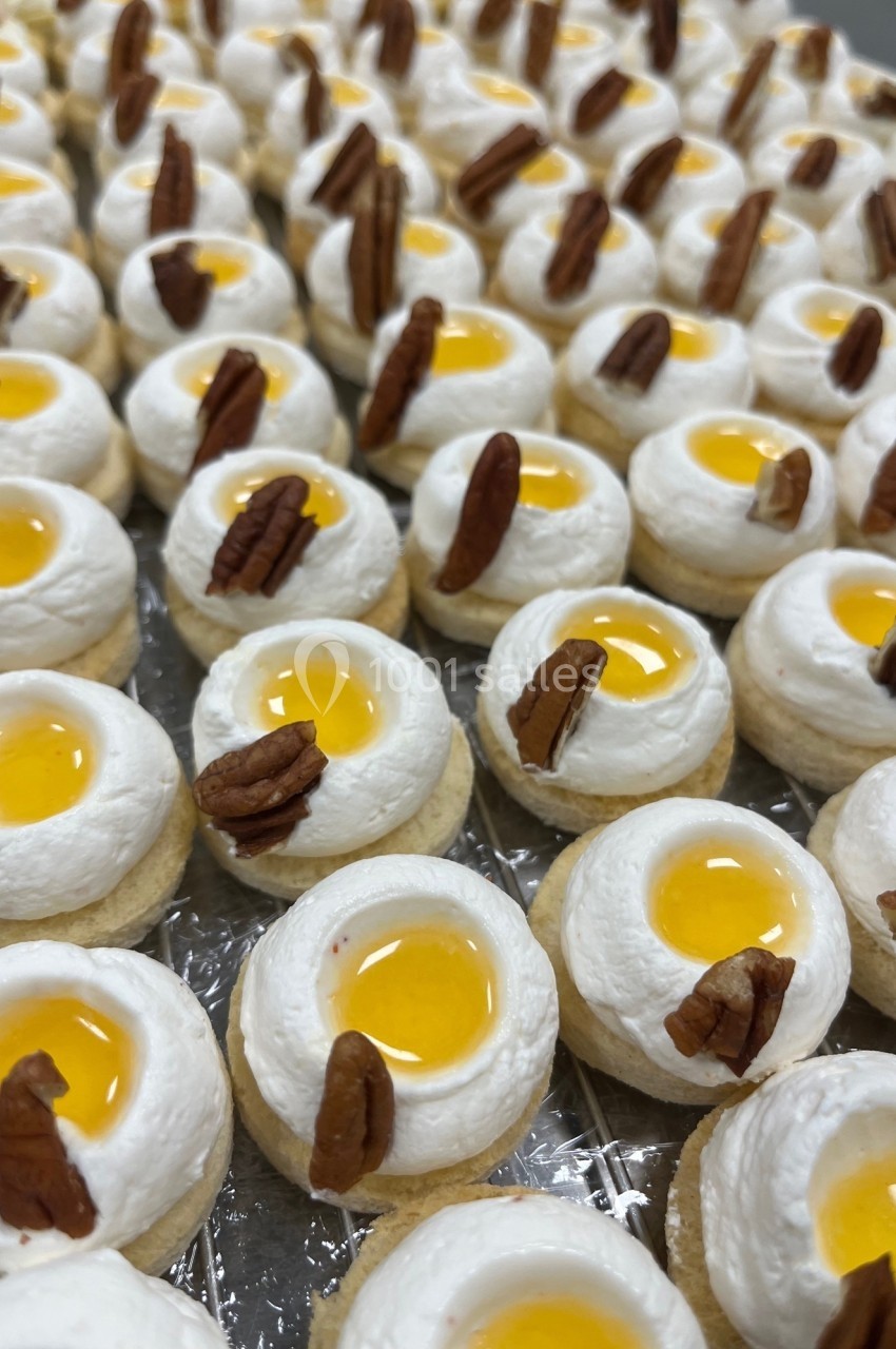 Petits desserts individuels garnis de crème, gelée jaune et décorés de morceaux de noix de pécan.