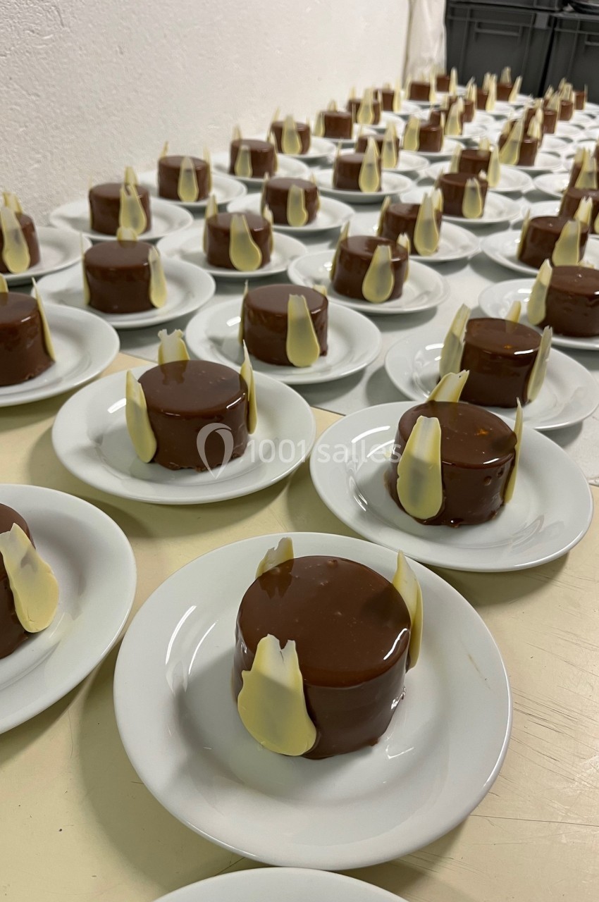Desserts individuels enrobés de chocolat brillant, décorés de morceaux de chocolat blanc, disposés sur des assiettes…