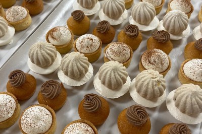 Miniature Traiteur Fréjus (Var) - La Cuisine By Alexandre #17 Salle de réception lumineuse avec tables rondes décorées de fleurs et vaisselle élégante, éclairée par des guirlandes.