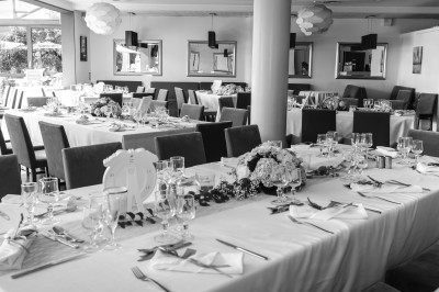 Salle de réception avec tables élégamment dressées, nappes blanches, chaises violettes et décorations florales.