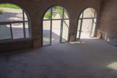 Cuisine professionnelle équipée avec plans de travail en inox, four, hotte d'extraction et portes en bois.