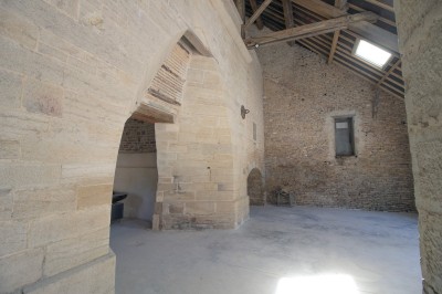 Cuisine professionnelle équipée avec plans de travail en inox, four, hotte d'extraction et portes en bois.