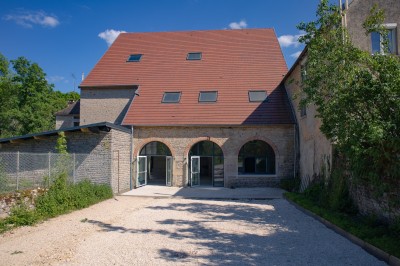 Cuisine professionnelle équipée avec plans de travail en inox, four, hotte d'extraction et portes en bois.