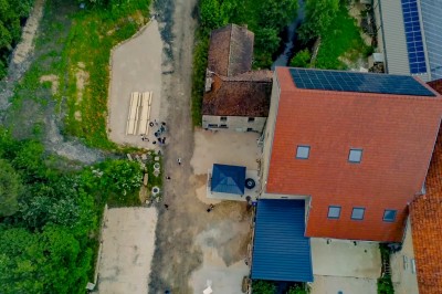 Cuisine professionnelle équipée avec plans de travail en inox, four, hotte d'extraction et portes en bois.