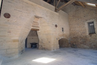 Cuisine professionnelle équipée avec plans de travail en inox, four, hotte d'extraction et portes en bois.