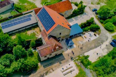 Cuisine professionnelle équipée avec plans de travail en inox, four, hotte d'extraction et portes en bois.