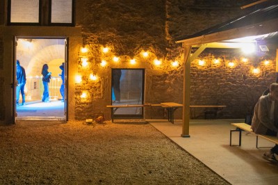 Cuisine professionnelle équipée avec plans de travail en inox, four, hotte d'extraction et portes en bois.