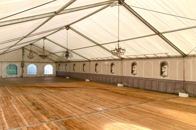 Couloir lumineux avec sol en damier, statues, tableaux accrochés aux murs et escalier en premier plan.