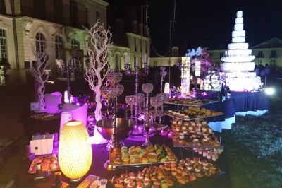 Couloir lumineux avec sol en damier, statues, tableaux accrochés aux murs et escalier en premier plan.