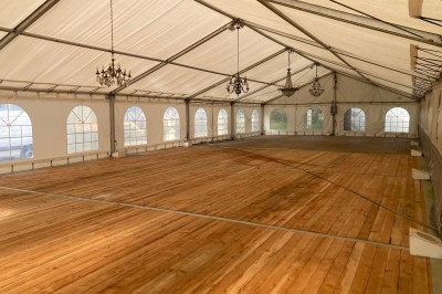 Cuisine ancienne avec une grande table en bois, un sol en pierre, des fenêtres lumineuses et des éléments rustiques.