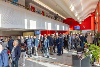 Une chanteuse en robe dorée se produit sur scène, entourée d'un chœur en tenues assorties, sous un éclairage bleu.