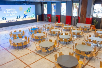 Une chanteuse en robe dorée se produit sur scène, entourée d'un chœur en tenues assorties, sous un éclairage bleu.