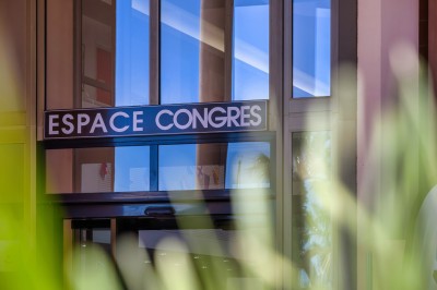 Une chanteuse en robe dorée se produit sur scène, entourée d'un chœur en tenues assorties, sous un éclairage bleu.