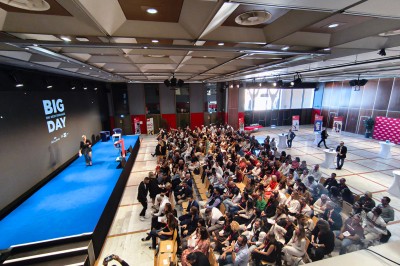 Une chanteuse en robe dorée se produit sur scène, entourée d'un chœur en tenues assorties, sous un éclairage bleu.