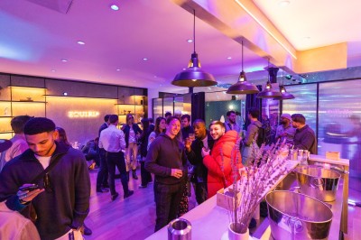 Salle moderne avec plafond végétalisé, éclairage violet, mobilier minimaliste et sol recouvert de tapis vert.