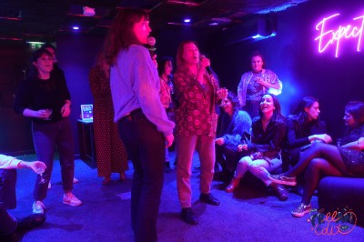 Salle moderne avec plafond végétalisé, éclairage violet, mobilier minimaliste et sol recouvert de tapis vert.