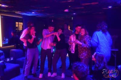 Salle moderne avec plafond végétalisé, éclairage violet, mobilier minimaliste et sol recouvert de tapis vert.