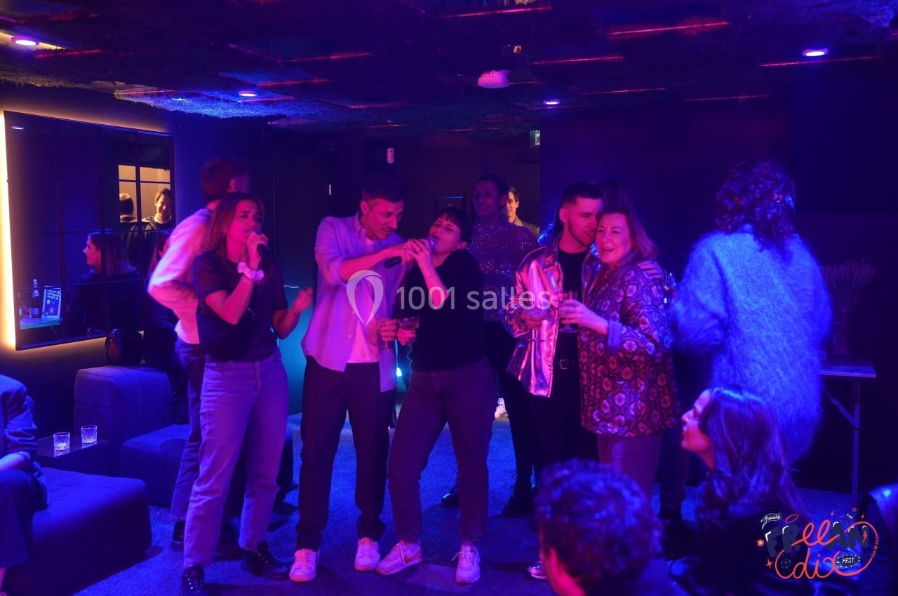 Un groupe de personnes chante et s'amuse dans une pièce sombre éclairée par des lumières colorées.