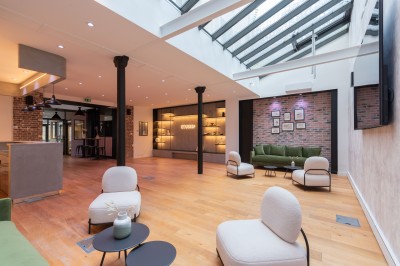 Salle moderne avec plafond végétalisé, éclairage violet, mobilier minimaliste et sol recouvert de tapis vert.