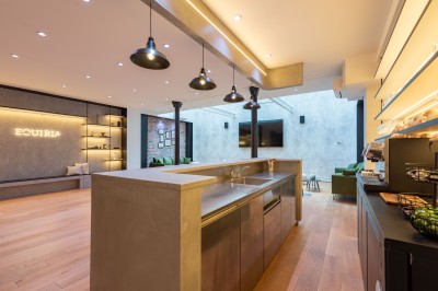 Salle moderne avec plafond végétalisé, éclairage violet, mobilier minimaliste et sol recouvert de tapis vert.