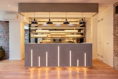 Salle moderne avec plafond végétalisé, éclairage violet, mobilier minimaliste et sol recouvert de tapis vert.