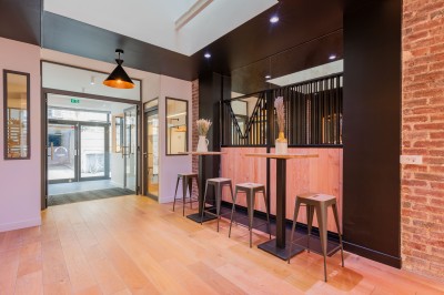 Salle moderne avec plafond végétalisé, éclairage violet, mobilier minimaliste et sol recouvert de tapis vert.